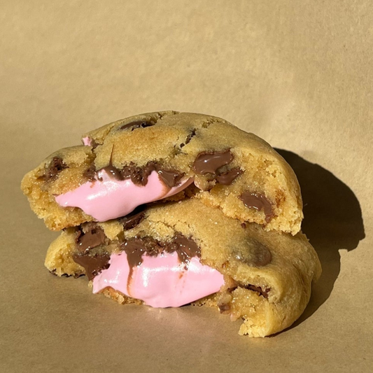 A chocolate chip smores cookie with marshmallow filling on a brown background